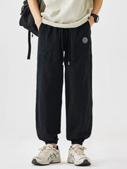 Black relaxed fit drawstring lounge pants with elastic cuffs and a logo patch.