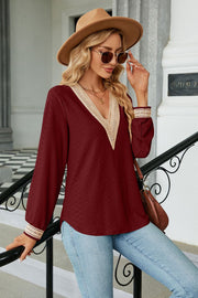 Burgundy textured V-neck blouse with lace trim and long sleeves.