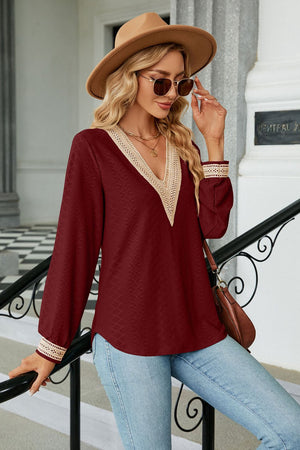 Burgundy textured V-neck blouse with lace trim and long sleeves.