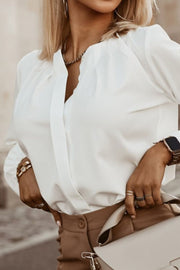 White pleated yoke blouse with button detail and V-neckline.