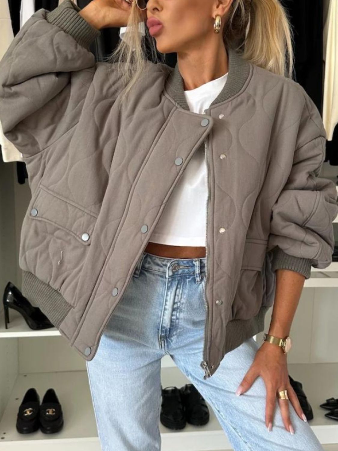 Taupe quilted bomber jacket with rounded sleeves and ribbed cuffs.