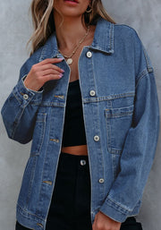Oversized denim trucker jacket in medium blue wash with button front and chest pockets.