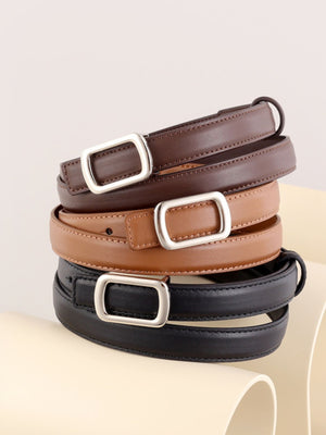 Leather skinny belts in brown, caramel, and black with silver buckles stacked.
