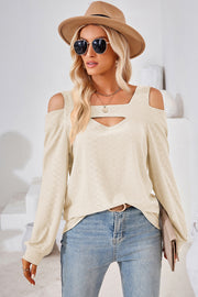 Cream geometric cutout shoulder top with a keyhole neckline and long sleeves.