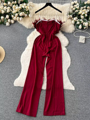 Wine red strapless wide-leg jumpsuit with feather trim and a belted waist.
