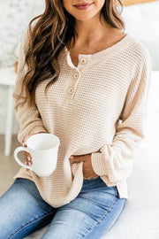 Cream waffle knit henley pullover sweater with button detail and relaxed fit.