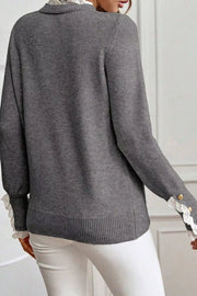 Dark gray knit sweater with mock neck, lace trim at collar and cuffs, and gold button details.