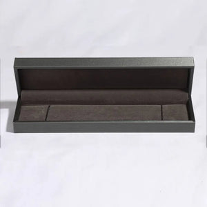 Empty dark gray jewelry box with brown velvet lining and dividers.