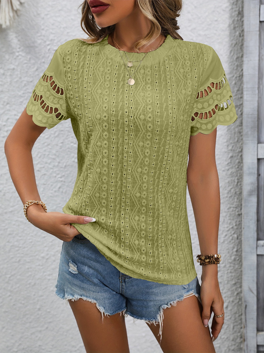 Sage green eyelet blouse with scalloped short sleeves and intricate patterned fabric.