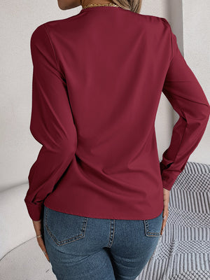 Burgundy V-neckline blouse with long sleeves and subtle pleating detail on the back.