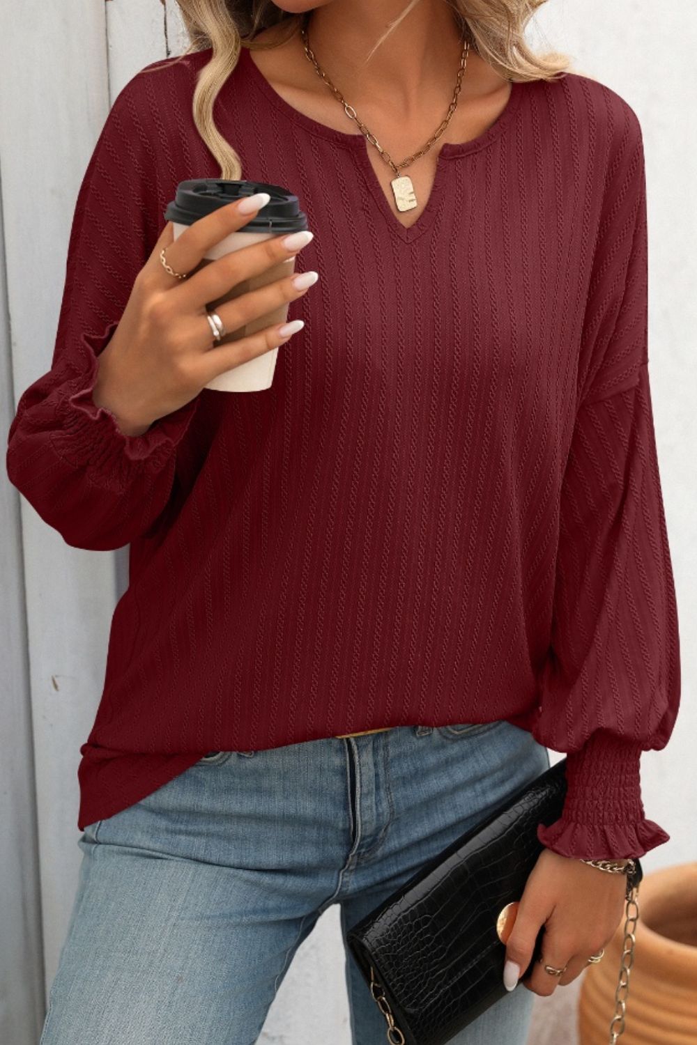 Burgundy textured sleeve blouson top with v-neck and smocked cuffs.