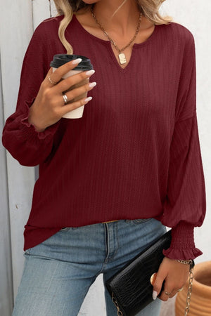 Burgundy textured sleeve blouson top with v-neck and smocked cuffs.