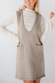Sleeveless knit pocket dress in camel with V-neck, styled over a ribbed mock neck top.