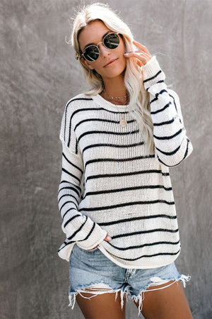 Relaxed white and black striped knit pullover sweater with crew neck and long sleeves.