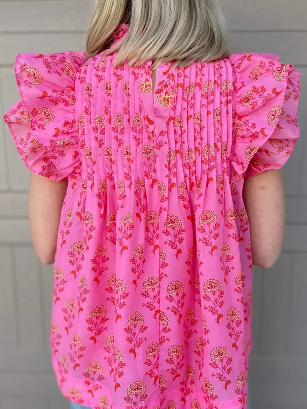 Pink floral print blouse with ruffled flutter sleeves and pintuck detail.