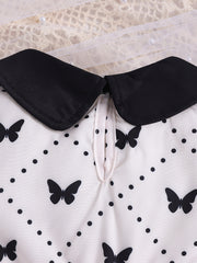 Baby dress with black collar, white fabric, and black butterfly & polka dot print.