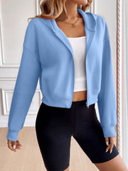 Light blue cropped hooded zip-up sweatshirt with a white tank top and black biker shorts.