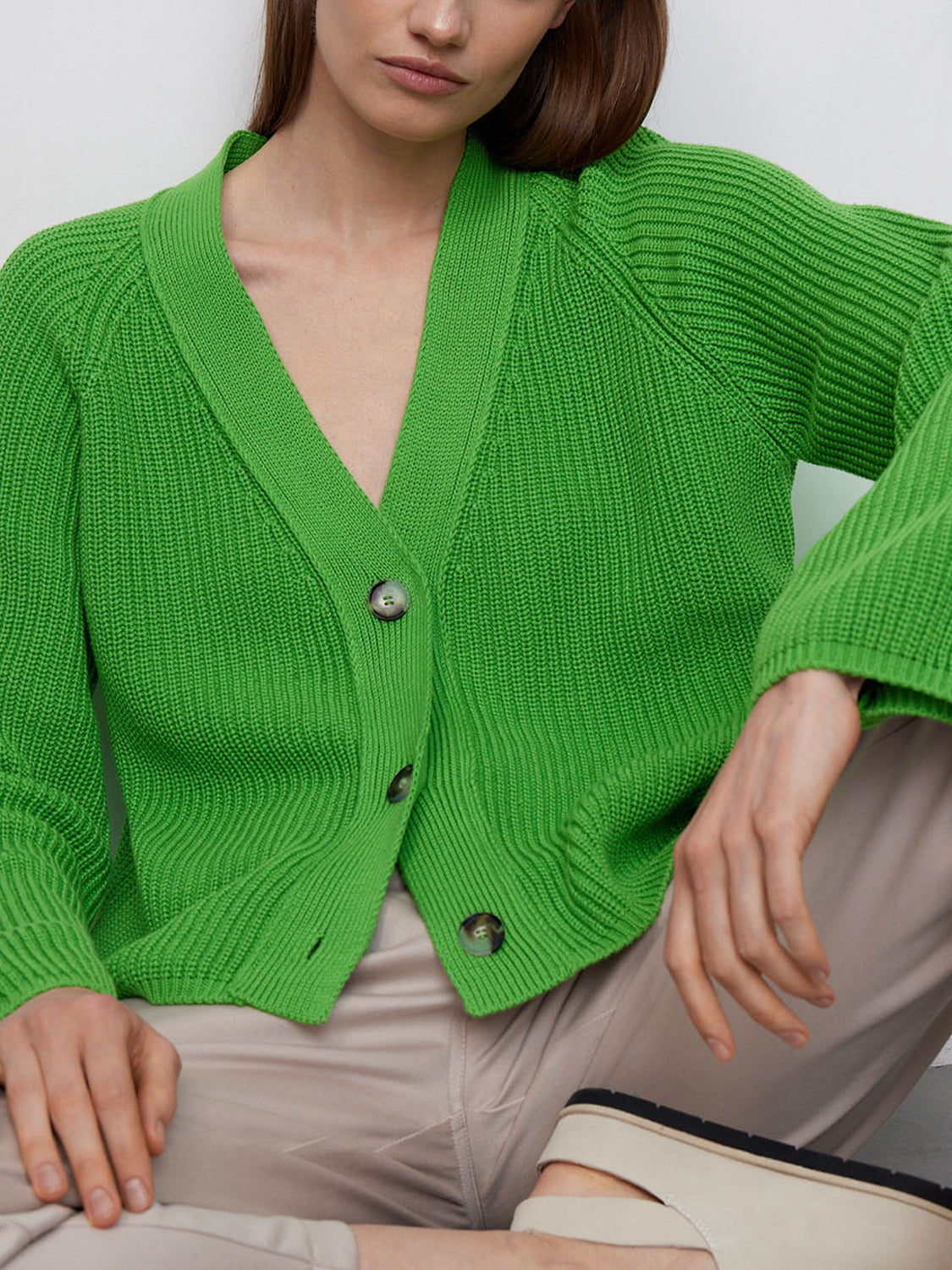 Green ribbed raglan cardigan with deep V-neck and button front detail.