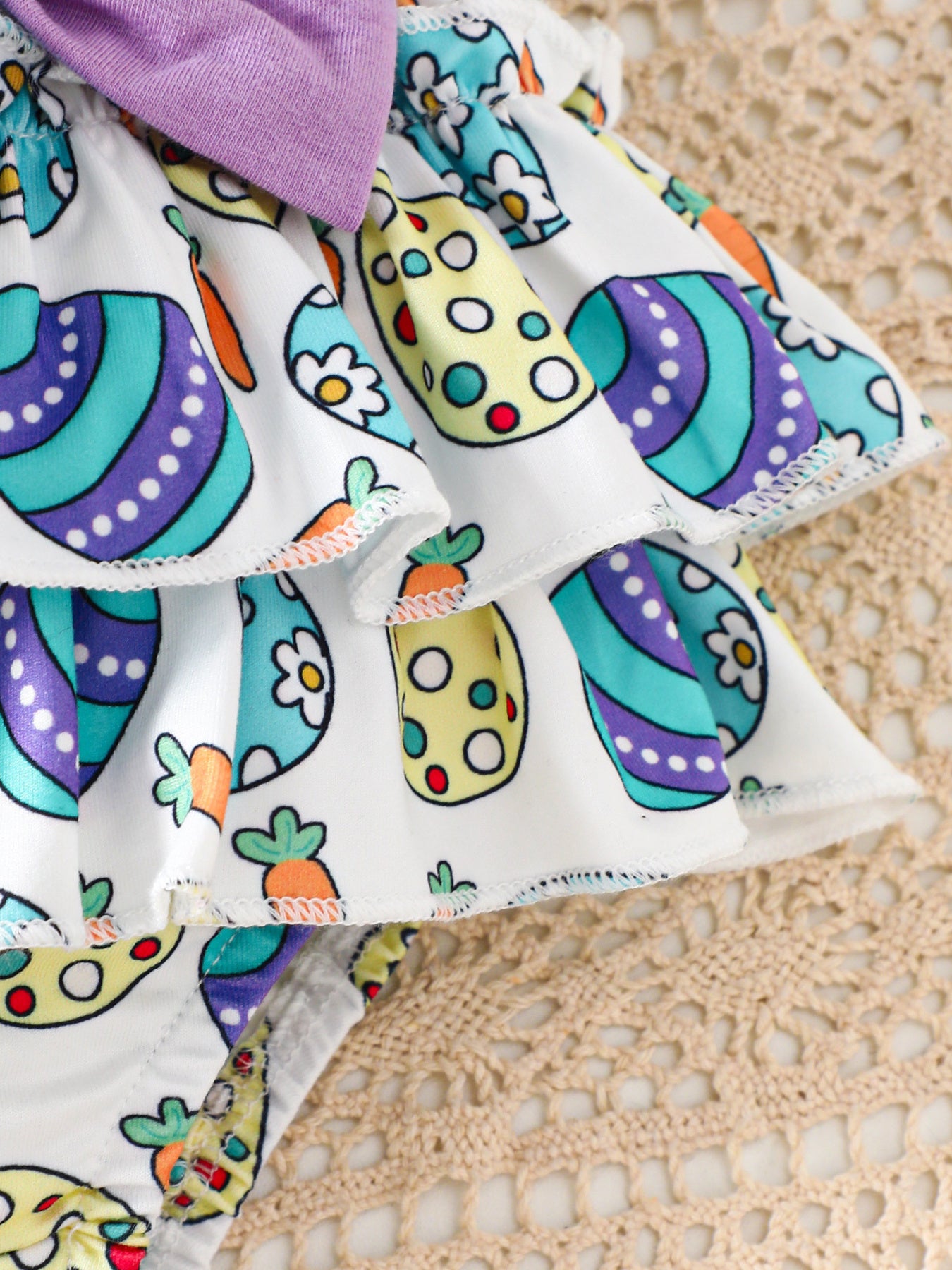 Easter graphic bodysuit and skirt set with carrot and egg print, purple bow detail.