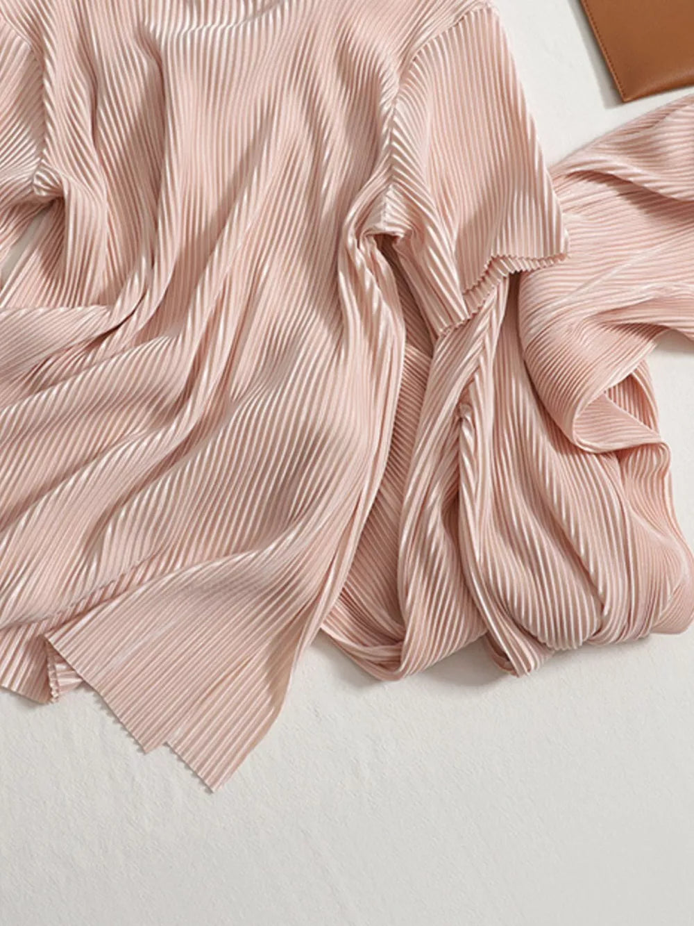 Elegant pink pleated two-piece set with a flowing drape and textured fabric.