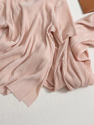 Elegant pink pleated two-piece set with a flowing drape and textured fabric.