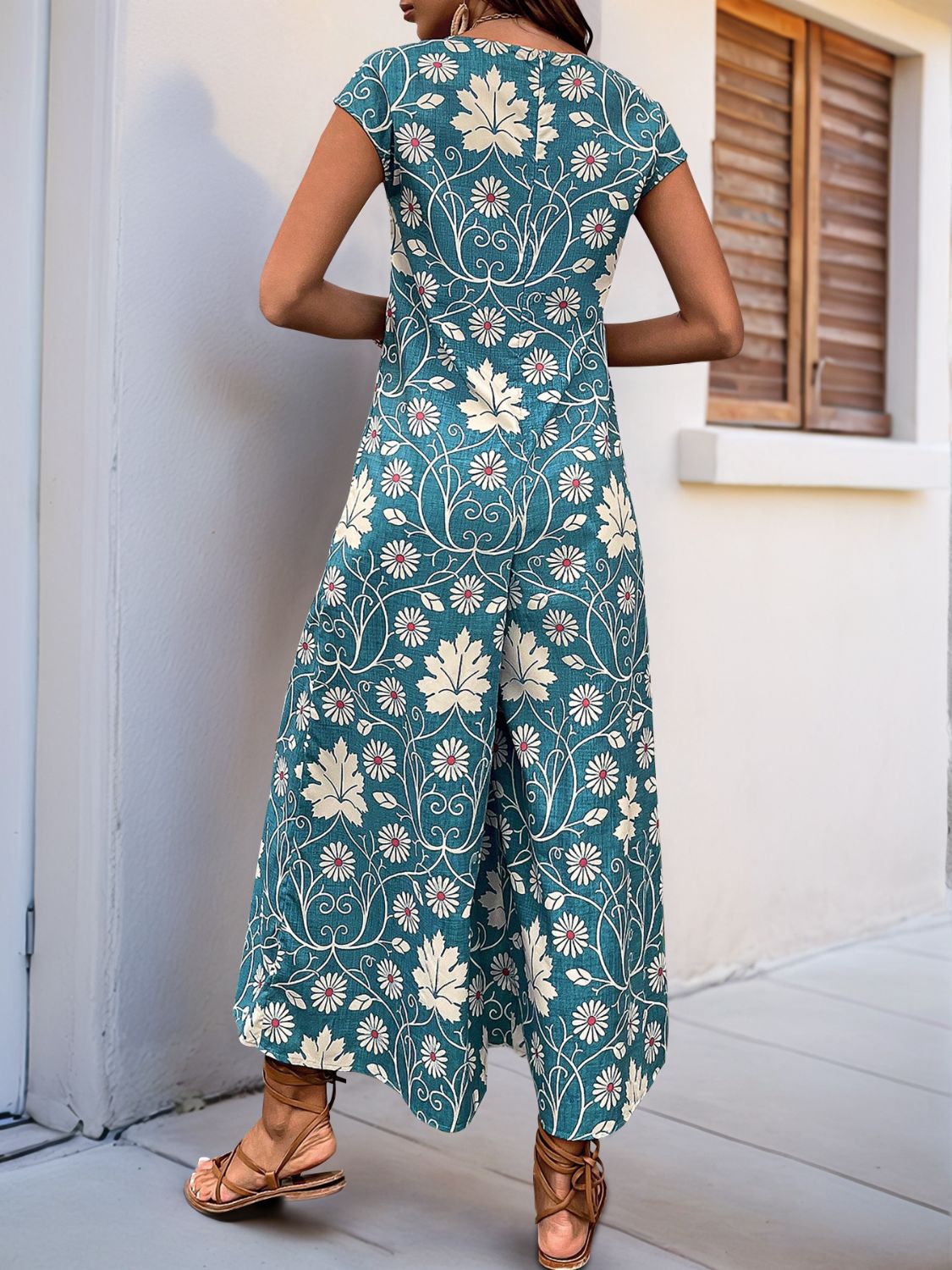Turquoise botanical print culotte jumpsuit with short sleeves and wide legs.