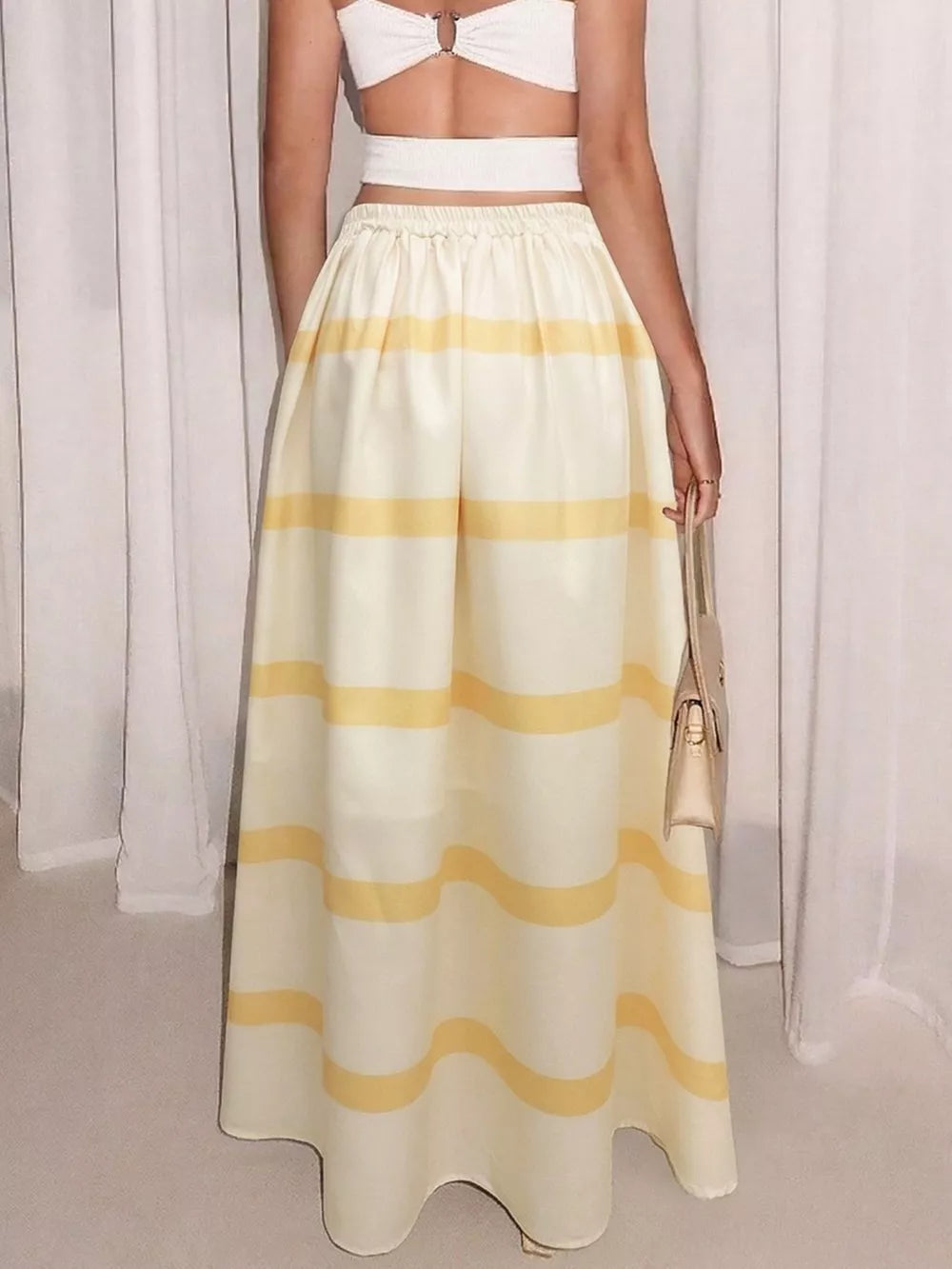 Flowy yellow and white striped maxi skirt with pockets, elastic waist, and a casual A-line cut.