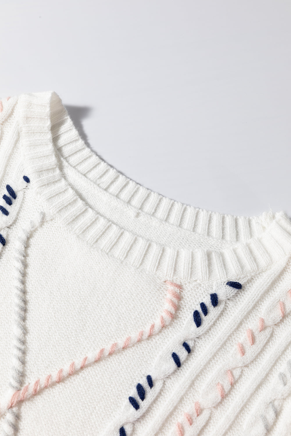 White cable knit sweater with embroidered details and puff sleeves.