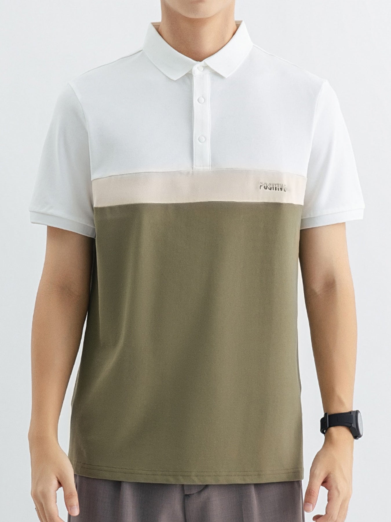 Men's color block polo shirt with white, beige, and olive green panels and embroidered text.