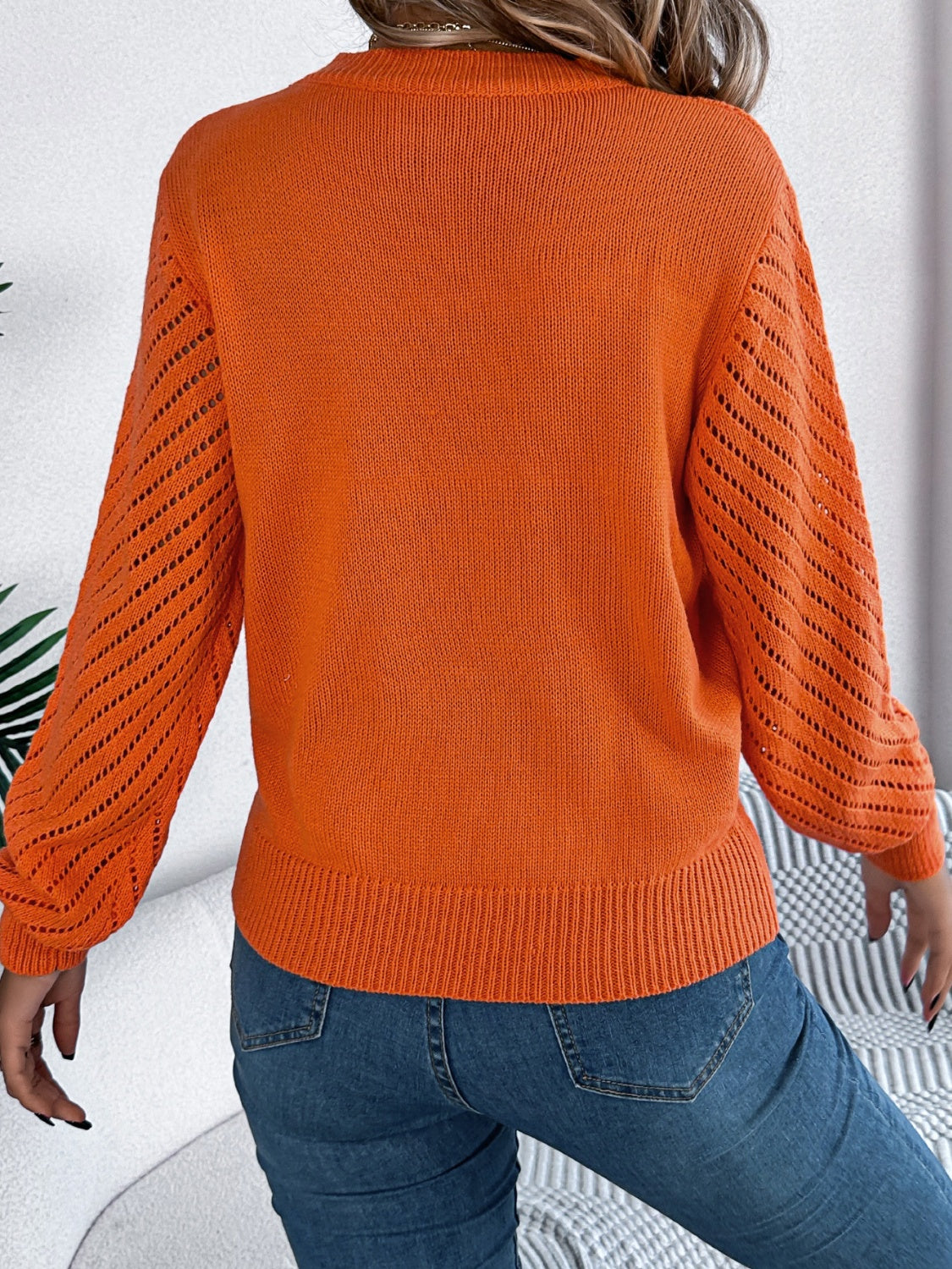 Orange knit sweater with openwork chevron blouson sleeves and ribbed hem.