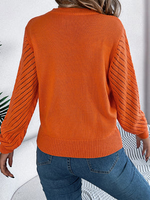 Orange knit sweater with openwork chevron blouson sleeves and ribbed hem.