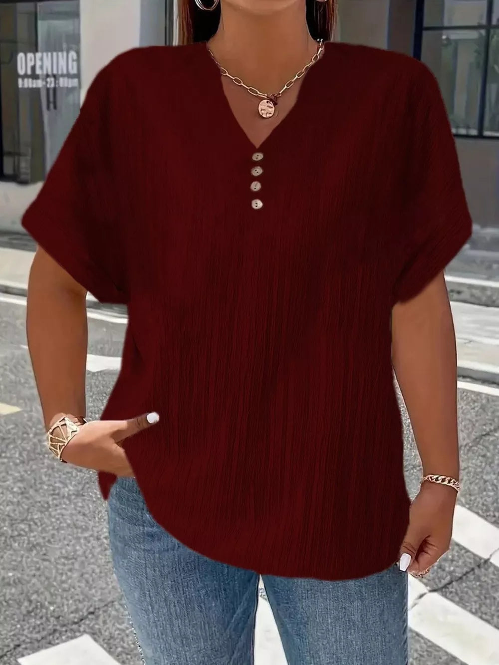 Textured wine red v-neck t-shirt with decorative buttons and short sleeves.