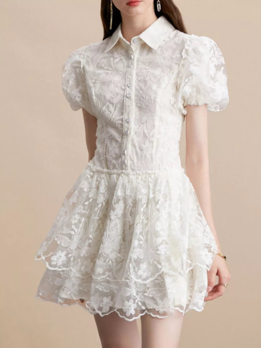 White lace mini dress with puff sleeves, buttoned front, and tiered skirt.