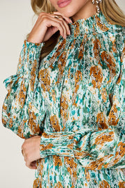 High neck abstract print blouse in green with smocked cuffs and neckline.