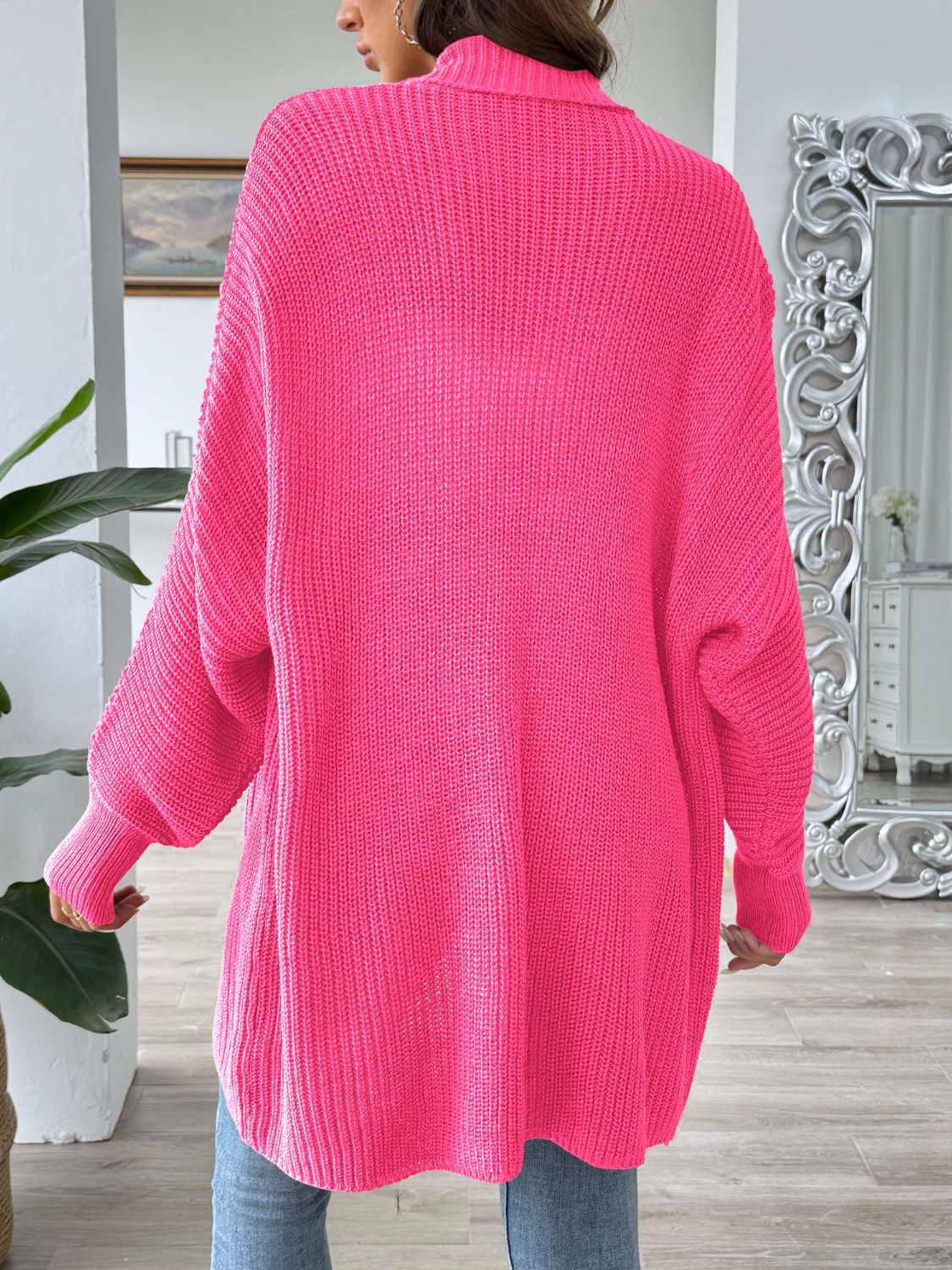 Pearl button ribbed knit cardigan in bright pink acrylic with a relaxed fit and long sleeves.