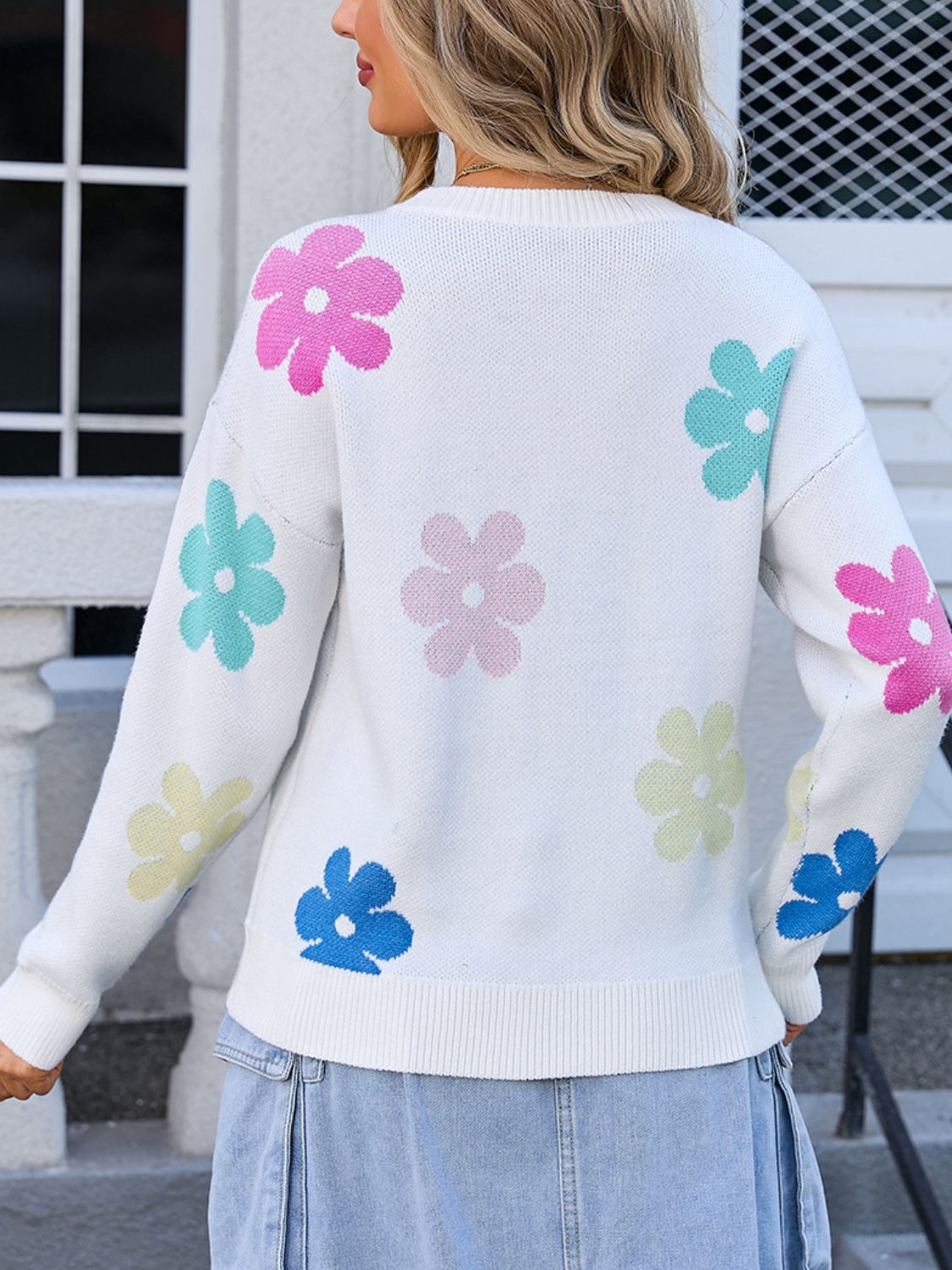 White crewneck sweater with a pastel floral print and ribbed cuffs and hem.