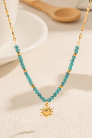 Gold celestial sunburst beaded necklace with turquoise beads and gold accents.