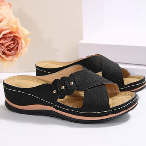 Black perforated cross-strap comfort sandals with adjustable closure and white stitching.