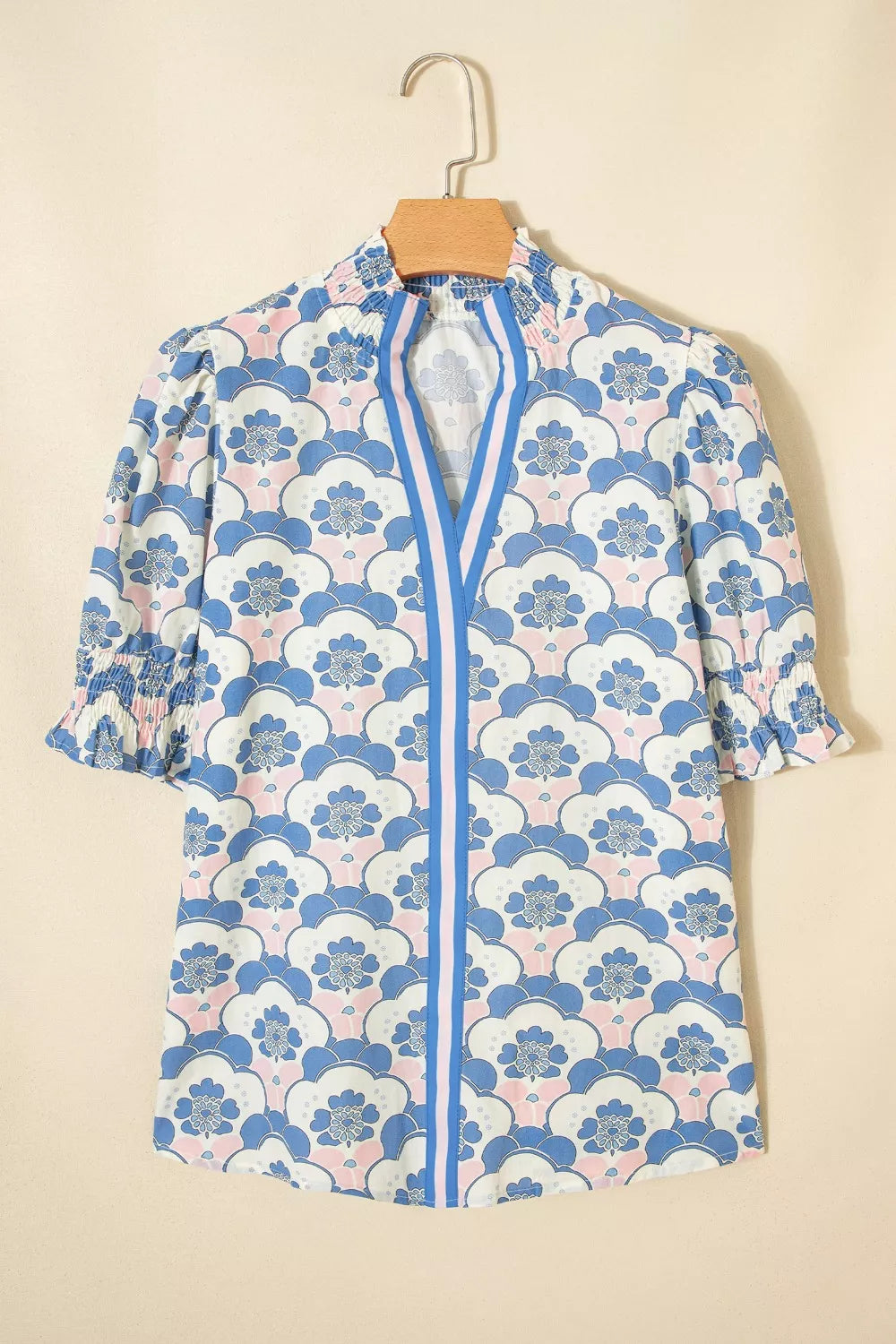 Playful floral puff sleeve blouse with smocked cuffs and neckline, featuring a blue and pink floral pattern.