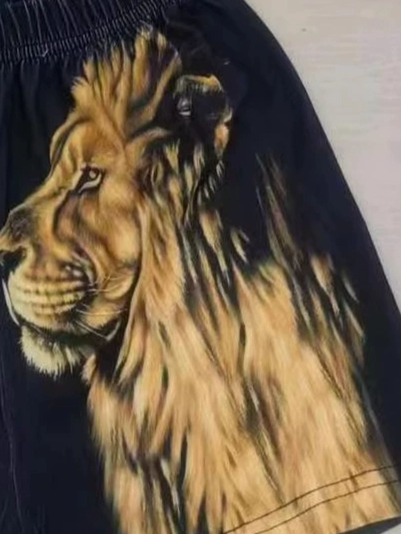 Black baby shorts with a regal lion graphic print and elastic waistband.