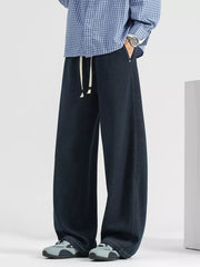 Men's dark wash loose fit drawstring jeans with white ties and side stitching.