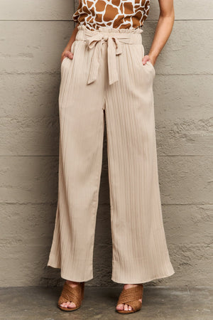 Pleated wide-leg paperbag waist trousers in apricot, made of 100% polyester, with a tie belt.