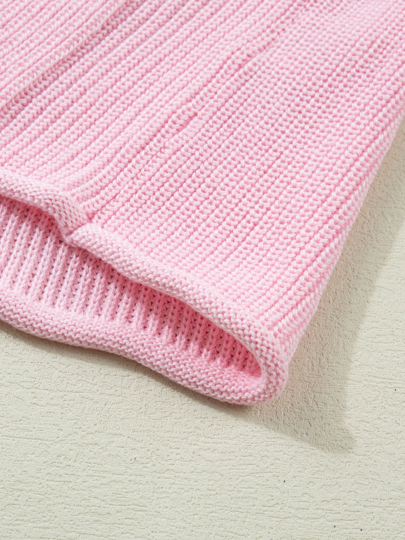 Pink acrylic knit sweater vest with ribbed texture and V-neck detail