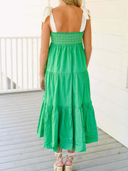 Green tiered midi dress with smocked bodice and tie shoulder straps.
