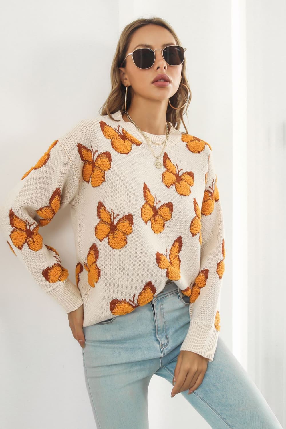 Beige acrylic knit crewneck pullover sweater with allover orange butterfly motif.