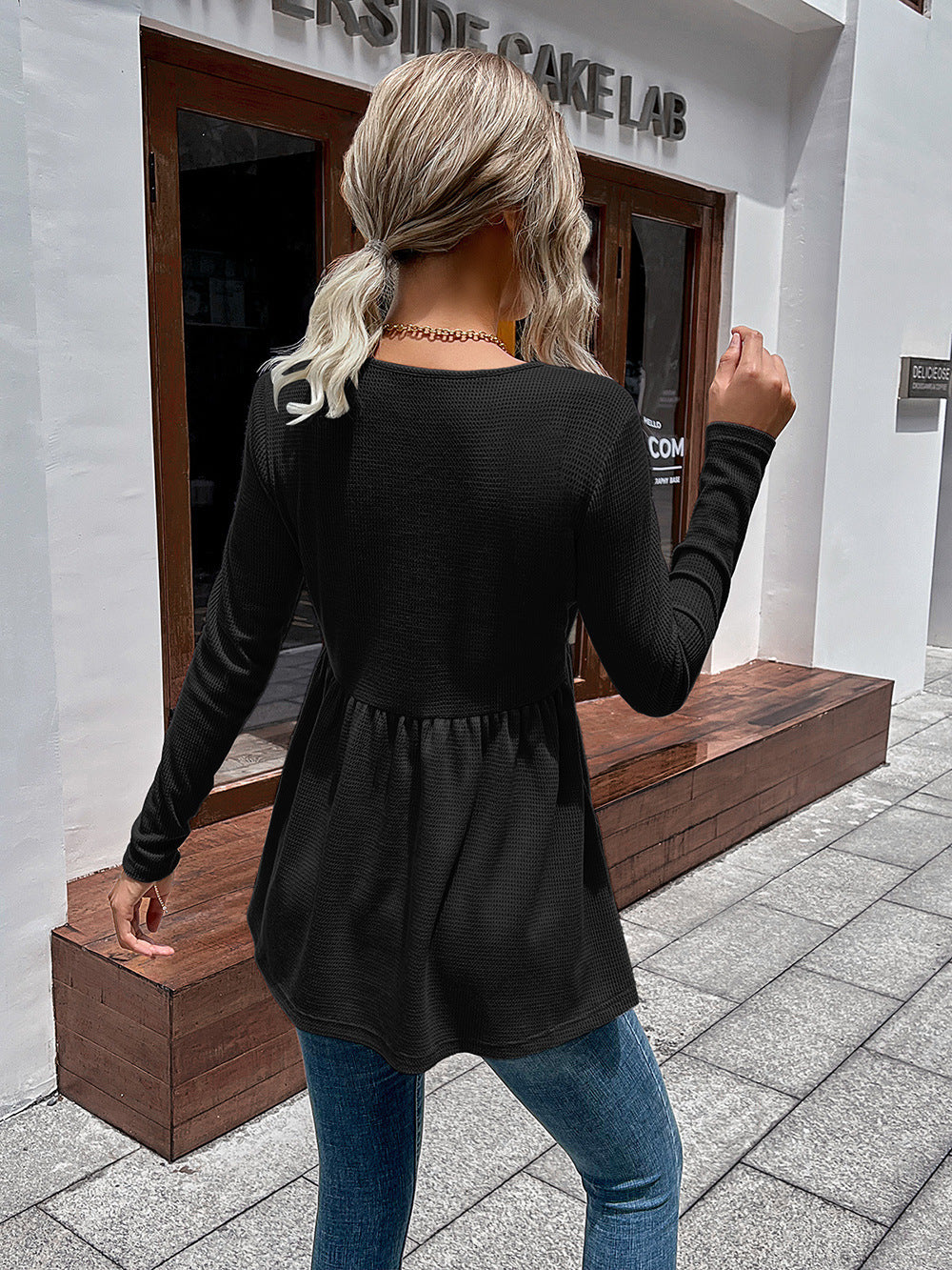 Black waffle knit peplum top with long sleeves and a gathered waist