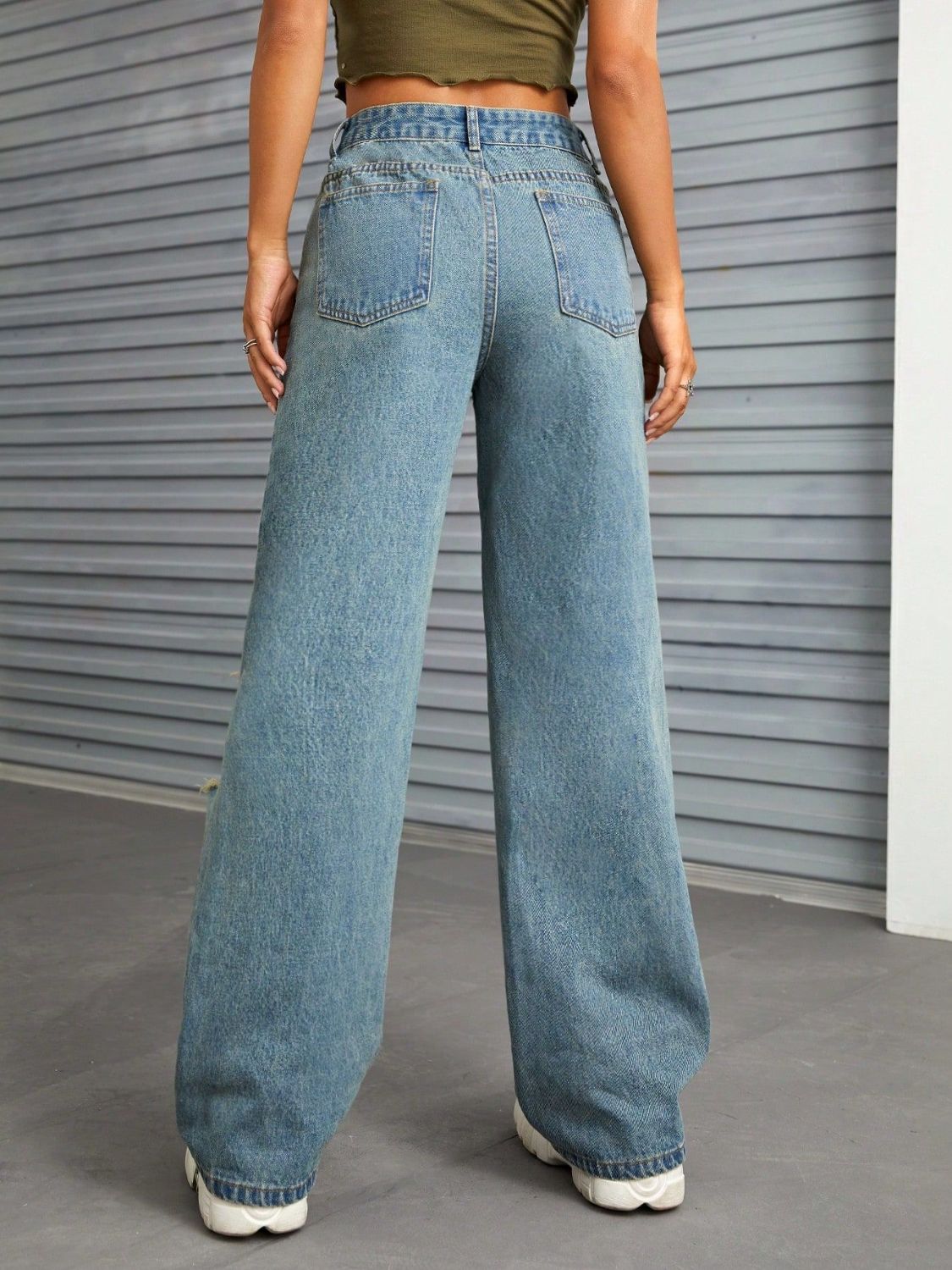 Distressed flare denim jeans in medium wash with raw edge detail and wide leg.