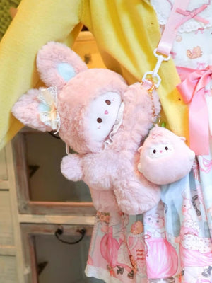 Pink plush bunny backpack with lace trim and a small sheep charm, attached to a pink strap.