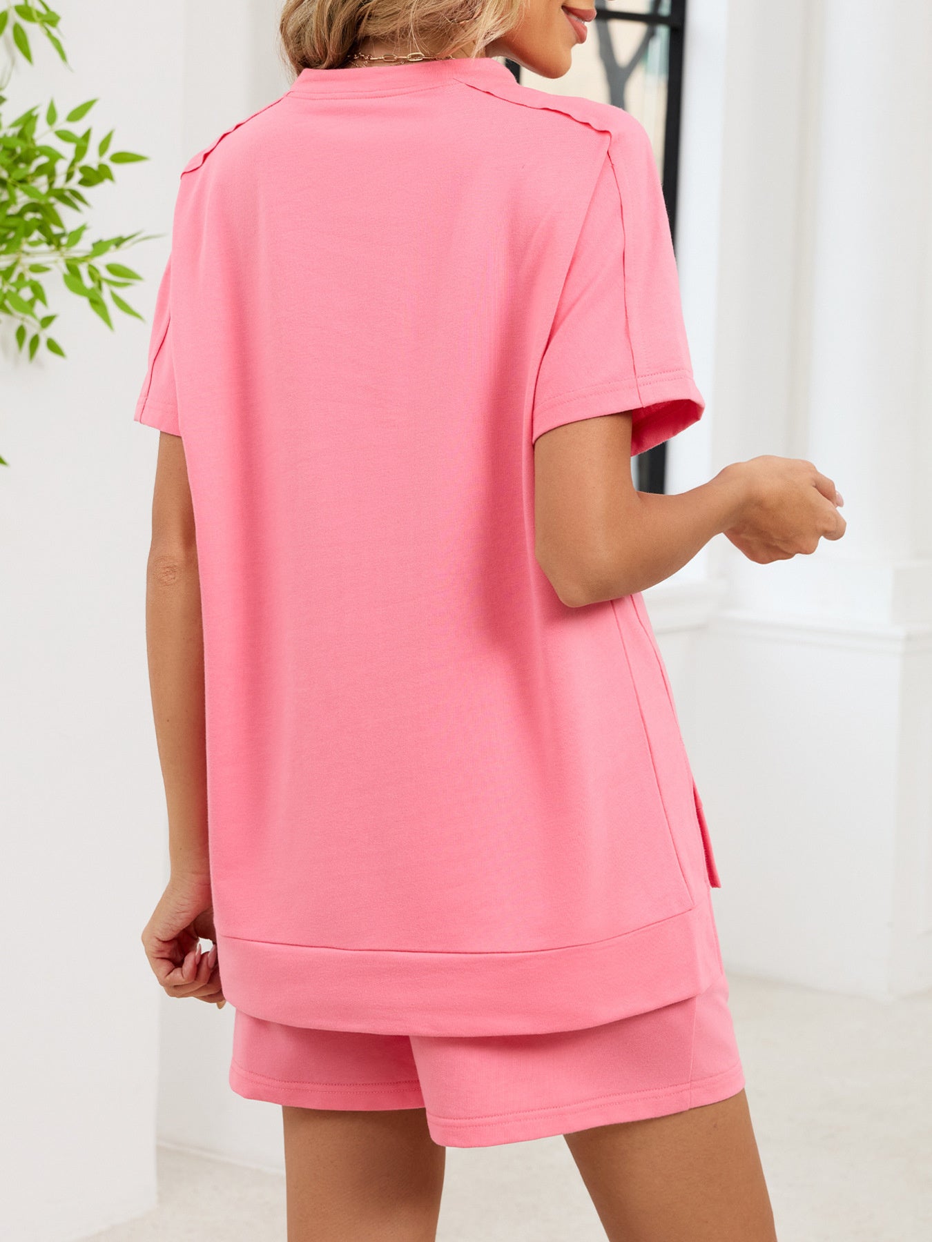 Pink relaxed two-piece set with short sleeves, crew neck, and side pockets on shorts.