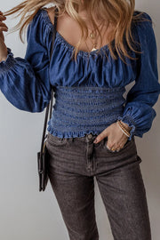Medium wash denim corset bodice blouson top with smocked waist and cuffs.